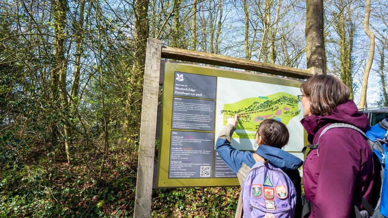 A mother and daughter look at a map marked with loop walks at Wenlock Edge